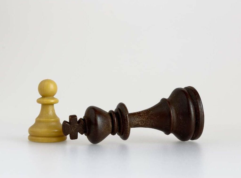 A fallen King chess piece next to a pawn