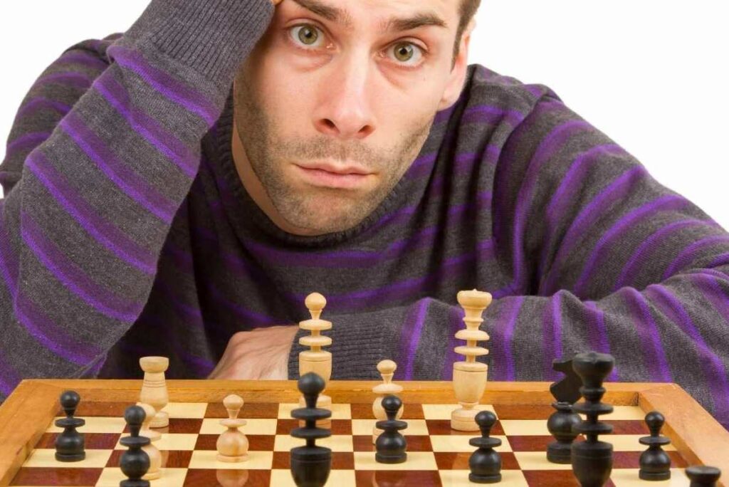 A man looking confused while staring at a chess board