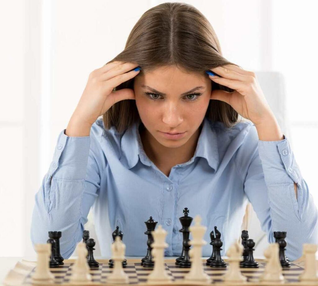 A woman staring at a chess board and pieces learning how to Analyze a Chess Game