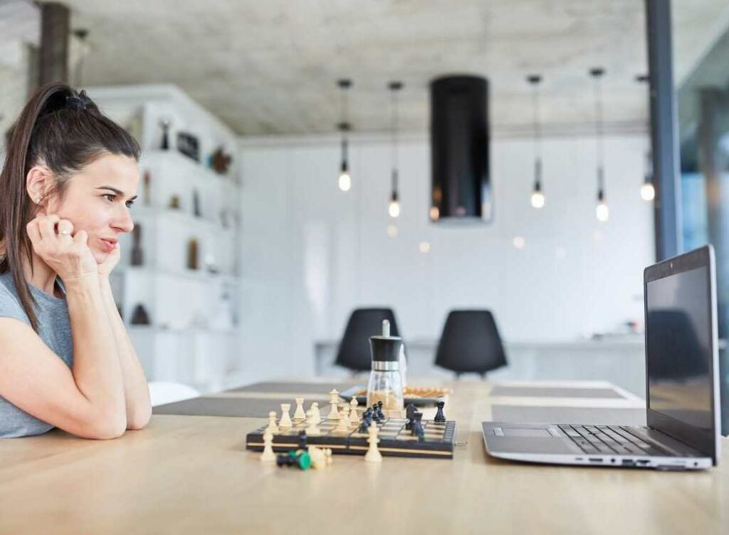 A woman with a laptop playing chess and learning how to Analyze a Chess Game