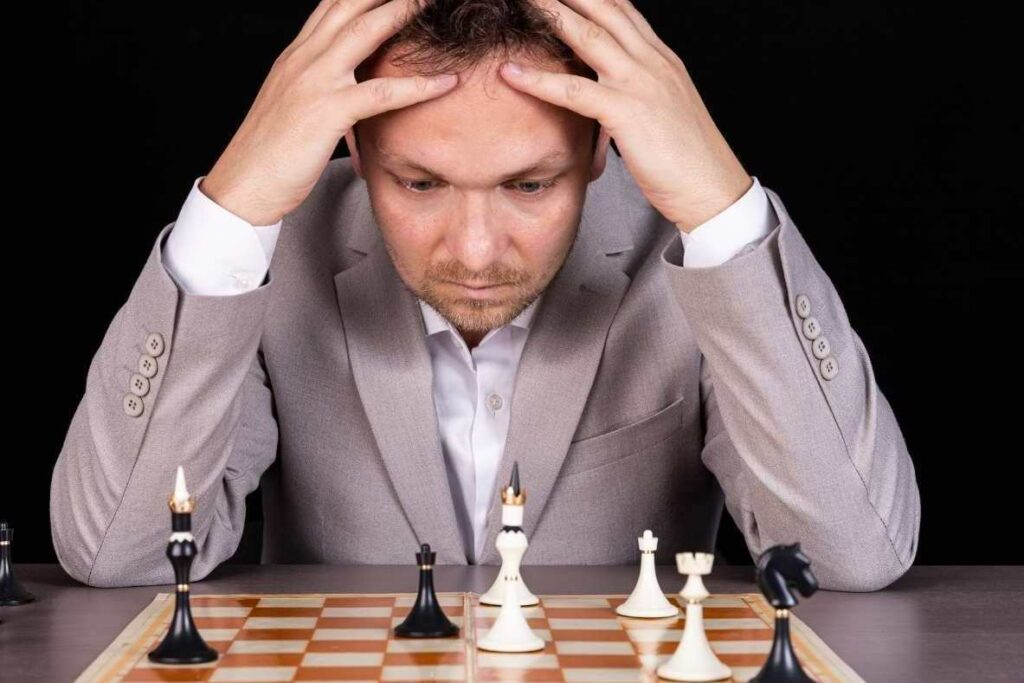 a man holding his head in his hands learning from his mistakes in chess