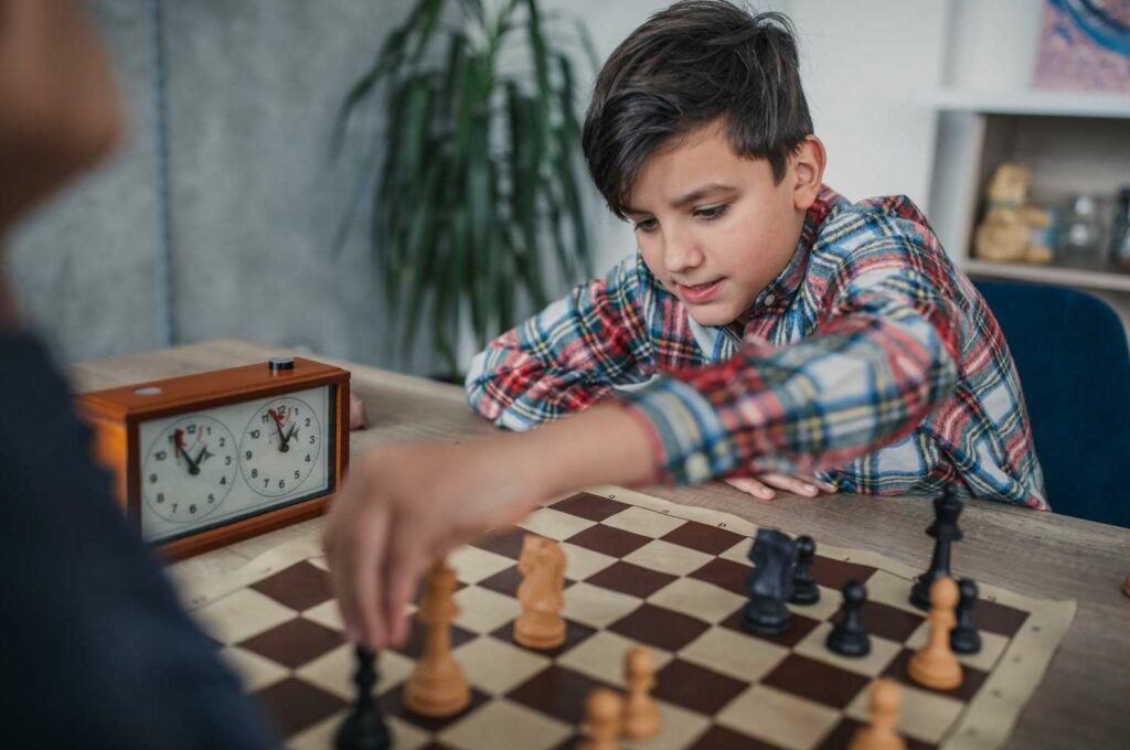 boy playing chess with timer next to him