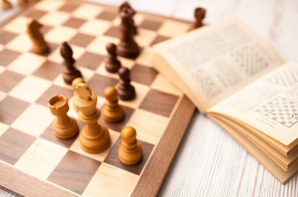 Book with chess moves and rules next to a chess board