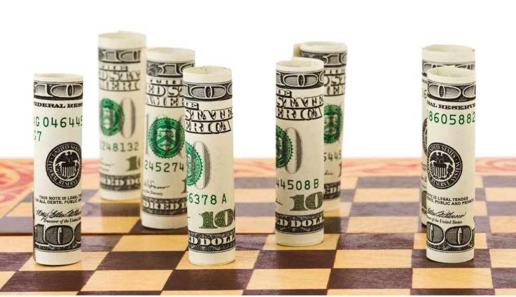 rolls of $100 bills on a chess board