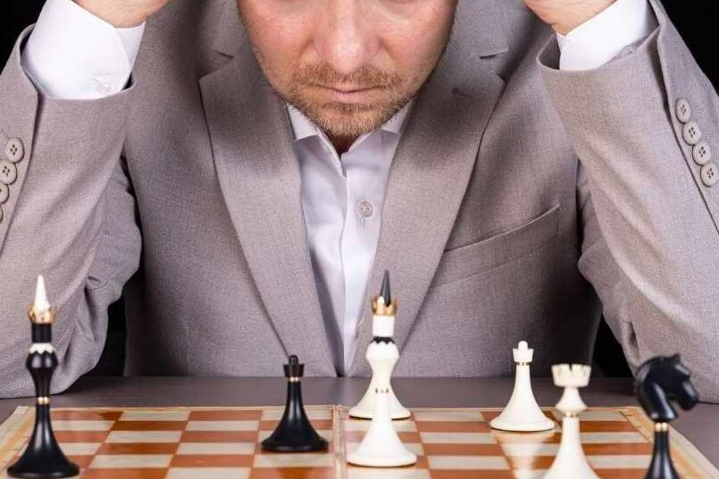 a man holding his head in his hands learning from his mistakes in chess