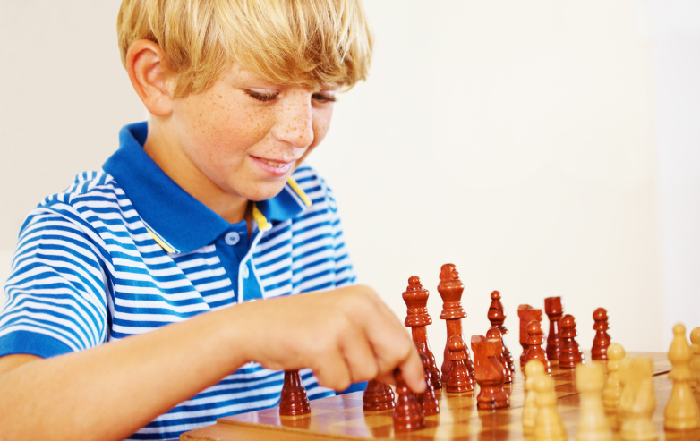 Smiling young boy learning chess