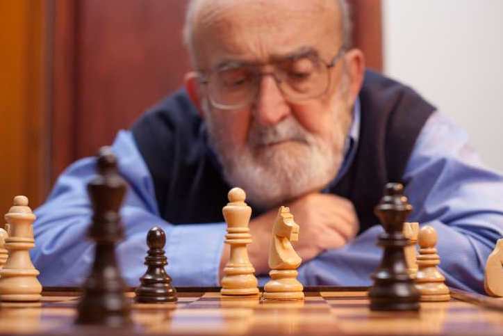 Older person playing chess with a large set
